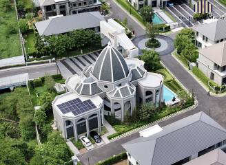 Aerial view of a modern residential building with a distinctive dome and solar panels on the roof