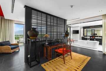 Modern living area with a view, featuring a desk, wicker chair, and bathtub