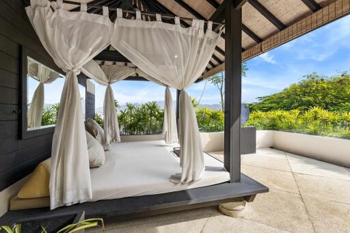 Outdoor bedroom area with canopy bed and garden view