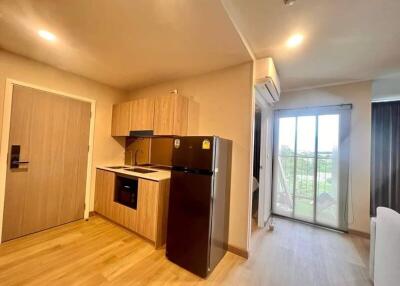 Compact kitchen with wooden cabinets, black appliances, and a view of a sliding door leading to a balcony.