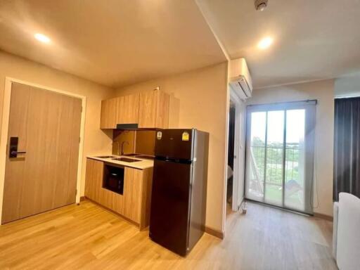 Compact kitchen with wooden cabinets, black appliances, and a view of a sliding door leading to a balcony.