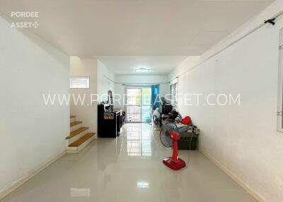 Spacious living area with glossy floor tiles, red standing fan, and large windows