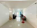 Spacious living area with glossy floor tiles, red standing fan, and large windows