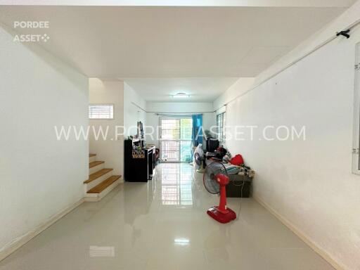 Spacious living area with glossy floor tiles, red standing fan, and large windows