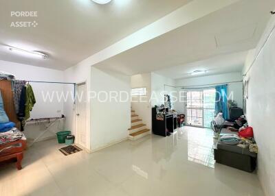 Spacious living room with staircase, bright tiled floors, and a mix of modern and traditional furniture