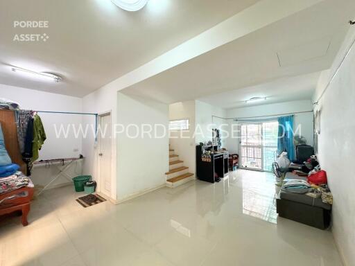 Spacious living room with staircase, bright tiled floors, and a mix of modern and traditional furniture