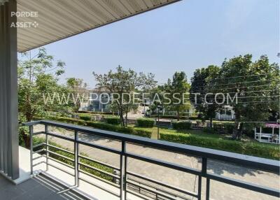 A balcony with a view of trees and a street