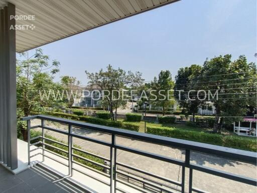 A balcony with a view of trees and a street