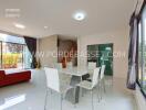 Modern dining area with white table and chairs, adjacent to living room with staircase and large windows.