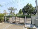 Exterior entrance to a gated property with trees and greenery