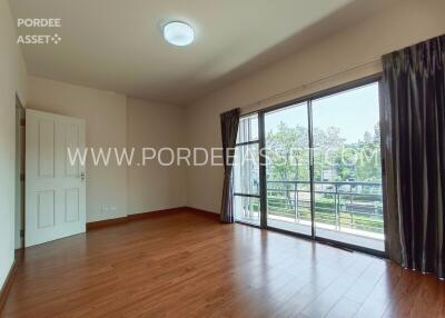 Spacious living room with wooden flooring and large sliding glass doors leading to a balcony