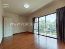 Spacious living room with wooden flooring and large sliding glass doors leading to a balcony