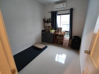 Simple bedroom with a window, air conditioning unit, and minimalist furniture