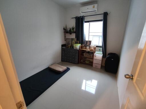 Simple bedroom with a window, air conditioning unit, and minimalist furniture