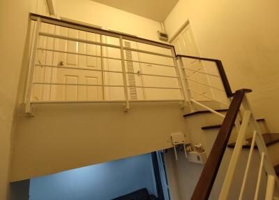 Indoor staircase with a white railing and a view of the upper landing and doors