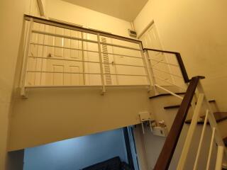 Indoor staircase with a white railing and a view of the upper landing and doors