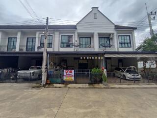 Front view of residential building with parked cars and a sale sign