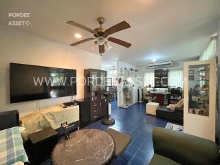 Living room with ceiling fan, wall-mounted TV, and furniture