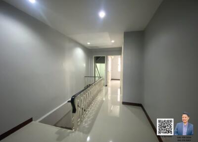 Bright and clean hallway with glossy tile flooring and a staircase