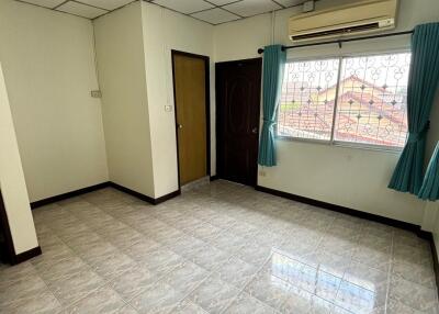 Living room with tiled floor, white walls, window with blue curtains, and ceiling air conditioning unit.