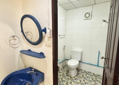 Picture of a compact bathroom with a blue sink and a circular mirror