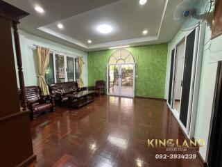 Spacious living room with wooden floor, green accent wall, and large windows