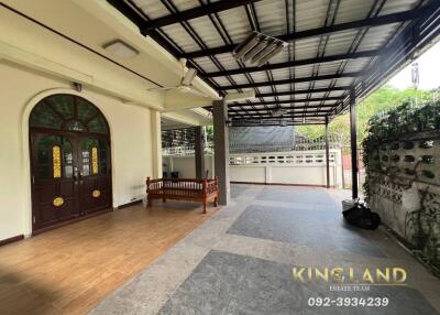 Covered outdoor patio area with wooden bench and tiled flooring