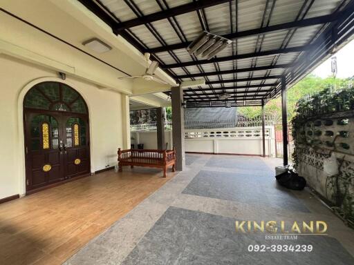 Covered outdoor patio area with wooden bench and tiled flooring