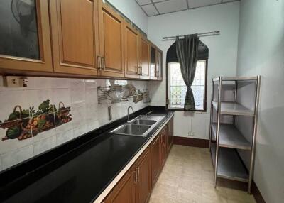 Modern kitchen with wooden cabinets, black countertop, and metal shelves