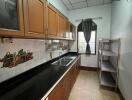 Modern kitchen with wooden cabinets, black countertop, and metal shelves