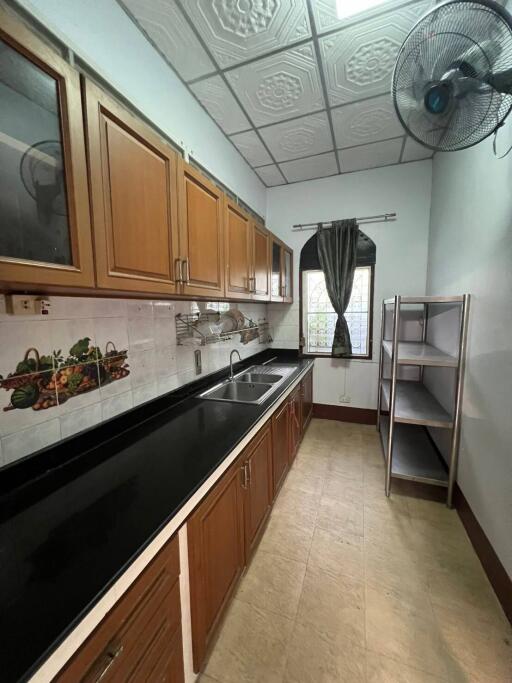 Modern kitchen with wooden cabinets, black countertop, and metal shelves