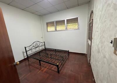 Simple bedroom with metal bed frame and wooden flooring