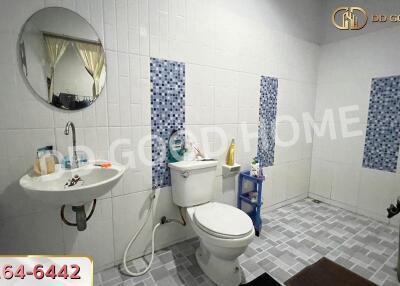 A bathroom with a sink, toilet, round mirror, and tiled walls