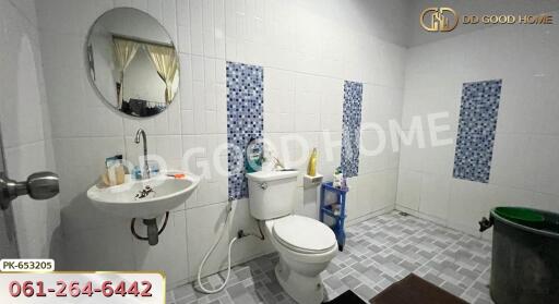 A bathroom with a sink, toilet, round mirror, and tiled walls