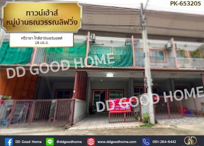 Front view of a residential building with visible signboards and green covers on the upper floor balcony.