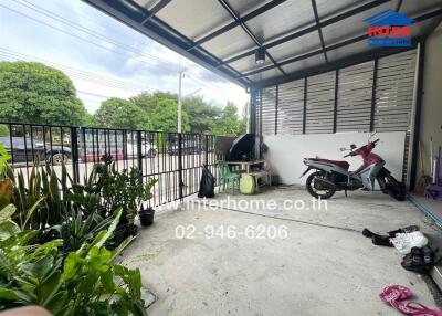 Covered outdoor area with potted plants and a motorbike