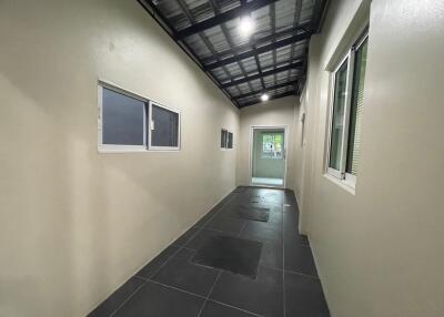 Narrow hallway with tiled floor and small windows