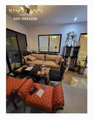 Modern living room with beige sofa, glass table, red cushioned stools, and decorative items