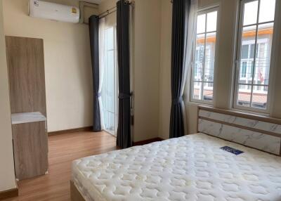 Bright bedroom with large windows and curtains, air conditioning, and access to a balcony