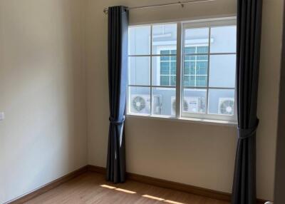 Bedroom with wooden flooring and large window with curtains