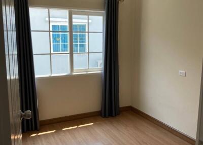 empty bedroom with wooden floor, window with closed curtains, air conditioner, and beige walls