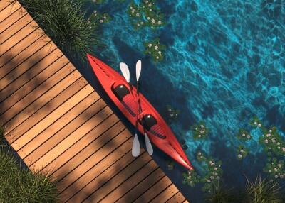 Wooden dock adjacent to a water body with a red kayak and paddles