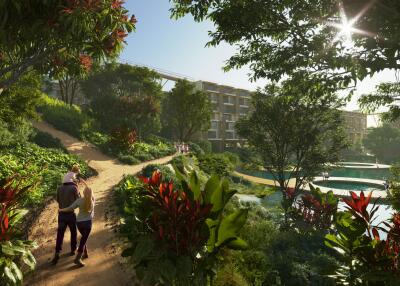 People walking on a pathway in front of a modern building complex surrounded by lush greenery