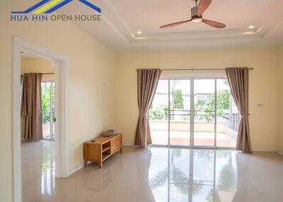 Spacious living room with ceiling fan and large windows leading to outdoor area