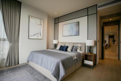 Modern stylish bedroom with large bed, side tables, art decor, and a view of a hallway.