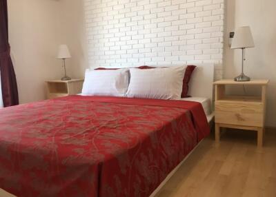 Modern bedroom with red bedding and brick accent wall