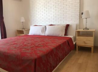 Modern bedroom with red bedding and brick accent wall