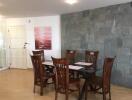 Dining room with wooden dining table and chairs, artwork and stone accent wall