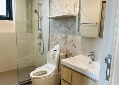 Modern bathroom with glass shower and herringbone tile accent wall