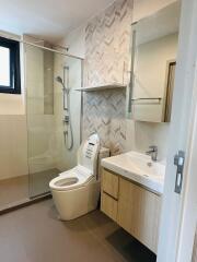 Modern bathroom with glass shower and herringbone tile accent wall